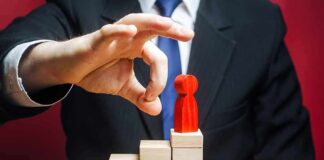 Businessperson hand above red figure on wooden block steps