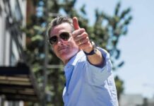 man in sunglasses giving a thumbs-up outdoors