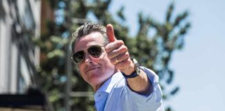 man in sunglasses giving a thumbs-up outdoors