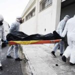 Race Against Ebola Hits Roadblocks medical team in hazmat suits carrying a body on a stretcher