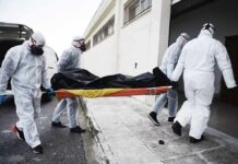 Race Against Ebola Hits Roadblocks medical team in hazmat suits carrying a body on a stretcher