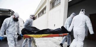 medical team in hazmat suits carrying a body on a stretcher
