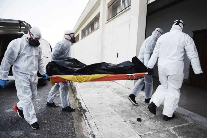 shutterstock_1693125517 medical team in hazmat suits carrying a body on a stretcher