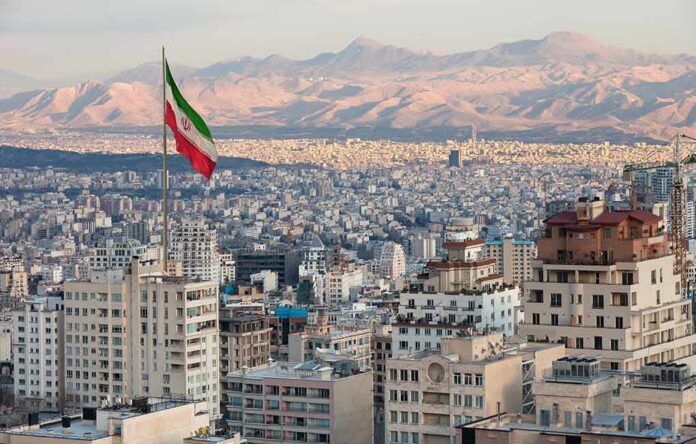 Iranian flag over a dense cityscape with mountains in the background