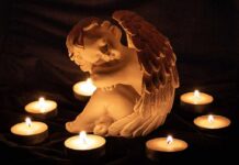 Drug Den Baby Death Sparks No-Bail Push angel statue surrounded by lit candles