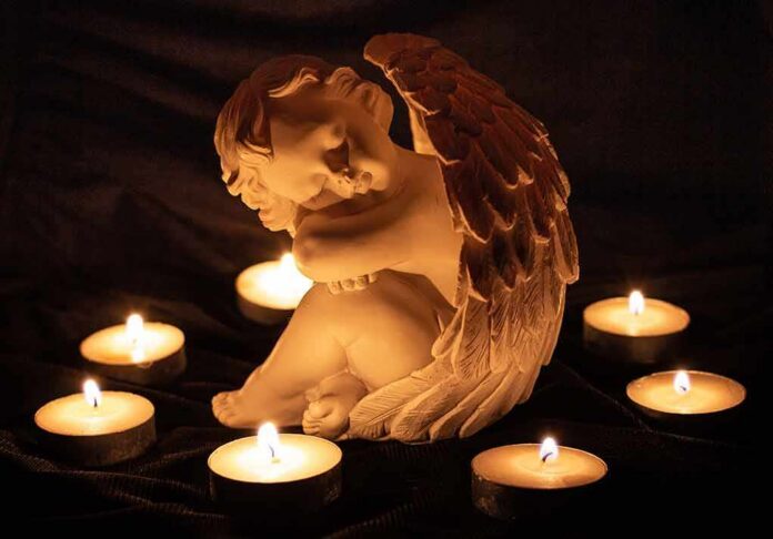 angel statue surrounded by lit candles