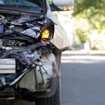Front of a car with severe collision damage and exposed headlight