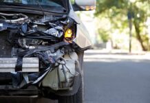 Front of a car with severe collision damage and exposed headlight