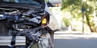 Front of a car with severe collision damage and exposed headlight