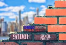 Brick wall with American flag and memorial text against city skyline