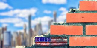 Brick wall with American flag and memorial text against city skyline