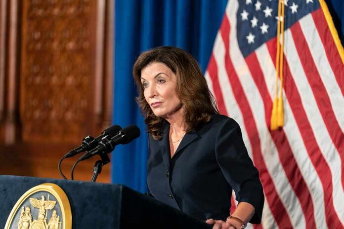 shutterstock_2023461065 Woman at podium speaking with microphones and U.S. flag behind