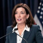 woman speaking at a podium with microphones