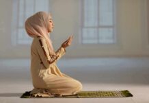 Woman in hijab praying on a mat indoors