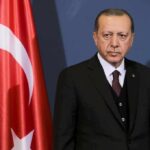 Censorship Blitz Hits Erdogan Challenger man in suit standing beside Turkish flag
