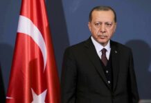 man in suit standing beside Turkish flag