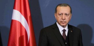 man in suit standing beside Turkish flag
