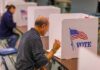 Man filling out ballot at voting booth