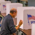 Man filling out ballot at voting booth