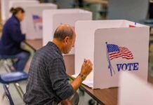 Man filling out ballot at voting booth