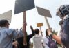 Group of people holding protest signs outdoors