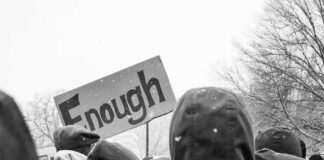 crowd in winter coats at a protest holding a sign