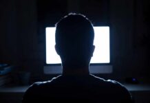 person silhouetted in front of a bright computer screen