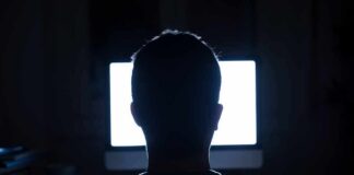 person silhouetted in front of a bright computer screen