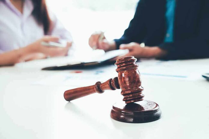 judge's gavel on table with people discussing documents in background