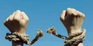 Shock Shift: Socialism Overtakes Big Business Hands breaking free from rope bindings against a clear blue sky