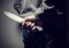 person holding a large knife behind their back