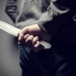 person holding a large knife behind their back
