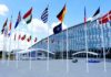 Row of national flags outside a modern glass building