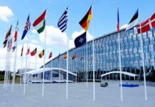 Europe Exposed? U.S. Drawdown Begins Row of national flags outside a modern glass building
