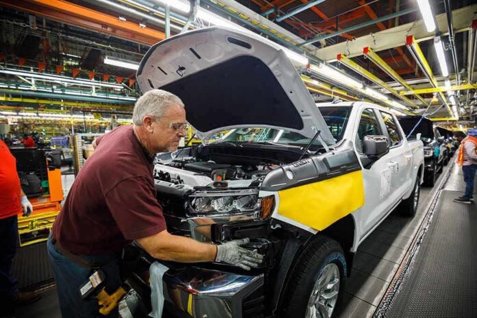 factory worker assembling a pickup truck on an automotive production line