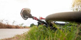 Road bicycle lying on grass beside a rural path
