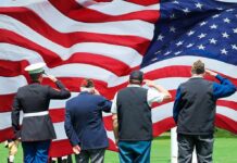 Veterans salute a large American flag