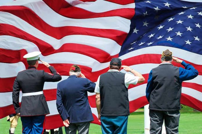 shutterstock_1174867879 Veterans salute a large American flag
