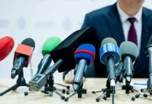 microphones clustered on a table at a press conference