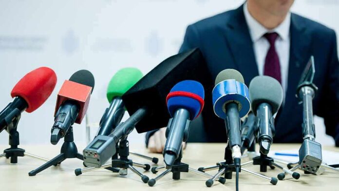 microphones clustered on a table at a press conference