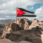 Palestinian flag waving over rocky desert cliffs