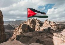 Palestinian flag waving over rocky desert cliffs