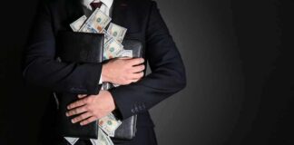 Businessman hugging briefcase stuffed with cash