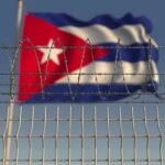 Barbed wire fence with Cuban flag in the background
