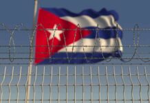 Barbed wire fence with Cuban flag in the background