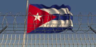 Barbed wire fence with Cuban flag in the background