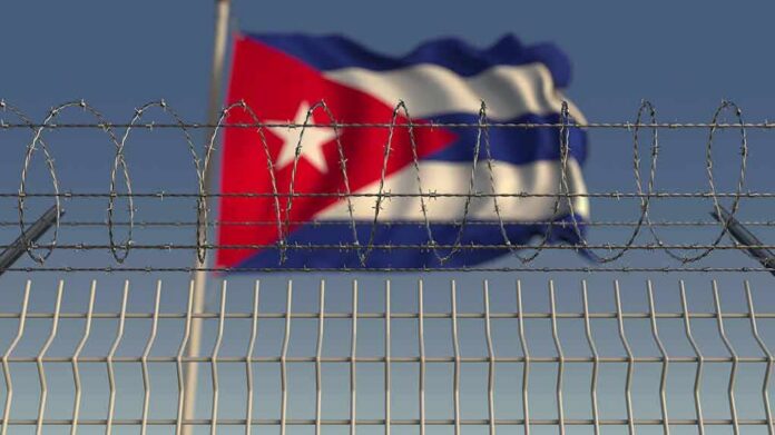 Barbed wire fence with Cuban flag in the background