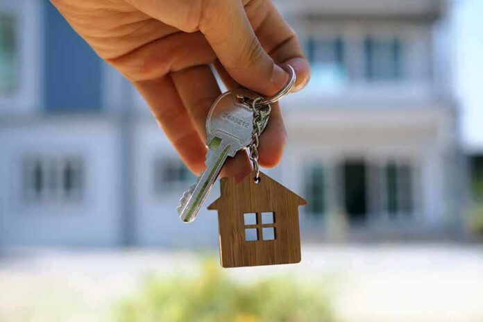shutterstock_1415127329 Hand holding house keys with a wooden house keychain