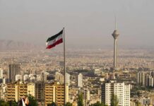 Iran Vows Pain – Trump Hints Something Bigger Iranian flag over Tehran skyline with Milad Tower