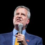 Bill de Blasio speaking into a microphone on stage